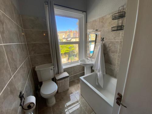 a bathroom with a toilet and a sink and a window at Peaceful Coastal Apartment in Ventnor