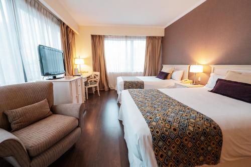 a hotel room with two beds and a couch and a tv at Amérian Buenos Aires Park Hotel in Buenos Aires