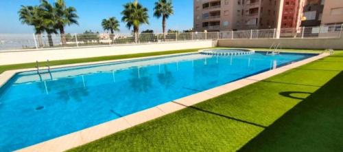 una gran piscina con césped junto a un edificio en Apartamento la manga, en La Manga del Mar Menor