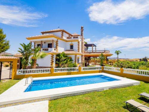 a villa with a swimming pool in front of a house at Cubo's Villa Fina & Minigolf included in Málaga