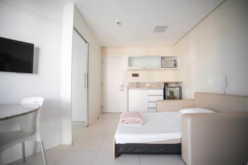 a small white room with a bed and a tv at Slaviero Ingleses Convention in Florianópolis