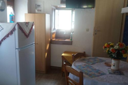 een keuken met een tafel en een witte koelkast bij Θέα in Kamarai