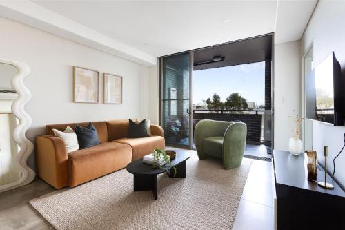 uma sala de estar com um sofá e uma cadeira em Kahlo Alexandria - Stylish 2 bdrm Walk to Train em Sydney