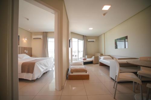 a hotel room with a bed and a table and chairs at Slaviero Ingleses Convention in Florianópolis