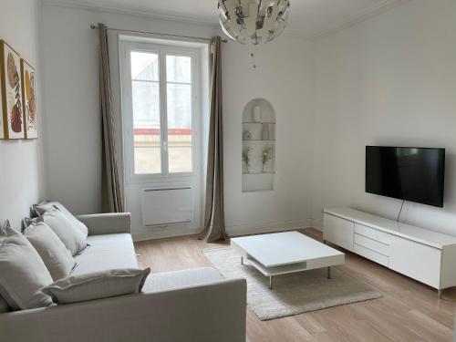 a white living room with a couch and a tv at Appartemment Nimes Arènes in Nîmes
