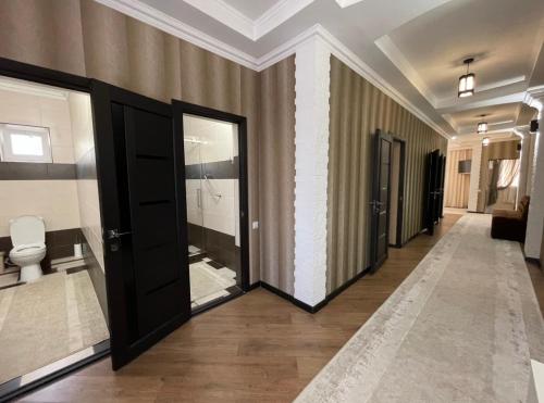 a hallway of a bathroom with a toilet and a door at Роща 7 in Bishkek