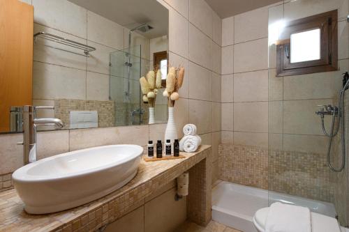 a bathroom with a white sink and a tub at Nikoleta Hotel and Villas in Limenas