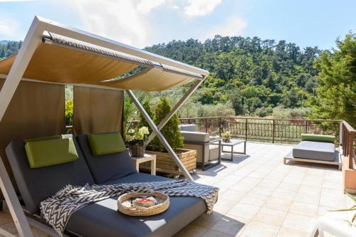 a patio with a bed and an umbrella at Nikoleta Hotel and Villas in Limenas