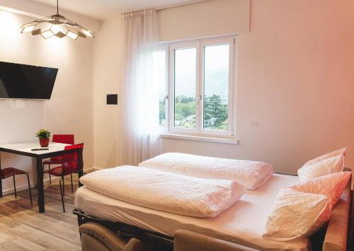 1 dormitorio con 2 camas, mesa y ventana en Lux - Studio-Appartment, en Merano
