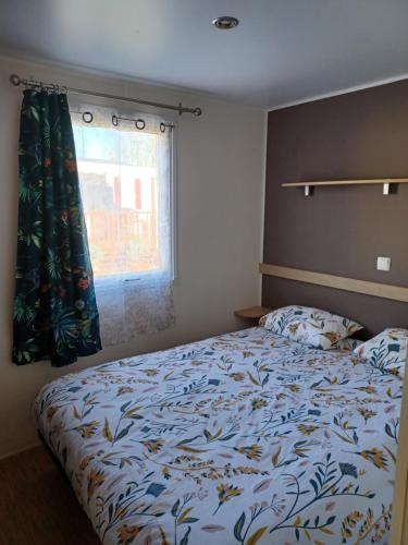 a bedroom with a bed and a window at Le Cosy, mobil-home 4-6 personnes au camping les Sables du Midi à Valras-Plage in Valras-Plage