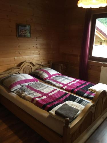 a bed in a log cabin with a bedspread on it at Reiterbauernhof Maho in Sankt Aegyd am Neuwalde