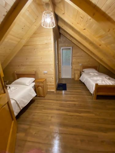 two beds in a room in a log cabin at Adenisi guesthouse in Tropojë