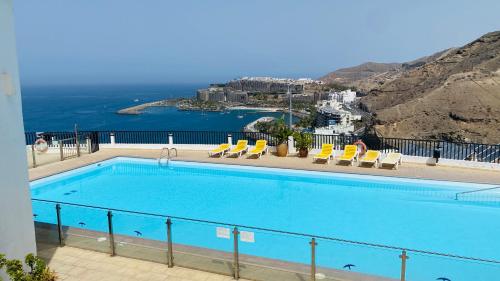 a swimming pool with chairs and a view of the ocean at Boho style bungalow with ocean view in Mogán