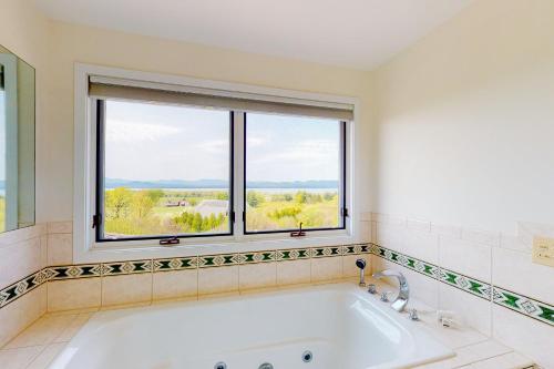 eine Badewanne im Bad mit Fenster in der Unterkunft Vermont Panoramic Lake View in Shelburne