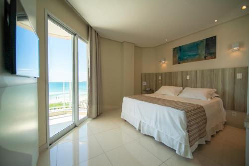 a bedroom with a bed with a view of the ocean at Slaviero Ingleses Convention in Florianópolis