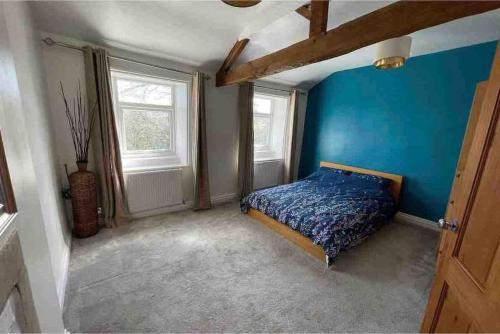 a bedroom with a blue wall and a bed at Brook Cottage in the heart of Yorkshire in Baildon