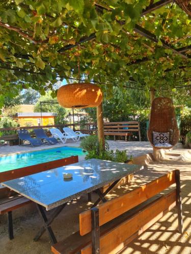 una mesa y bancos bajo un árbol con piscina en Cabañas Refugio Nativo, en Santa Cruz