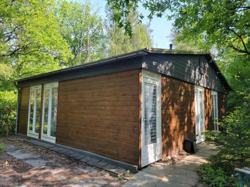 een klein bruin gebouw met ramen in het bos bij Bungalow in het bos in Nunspeet