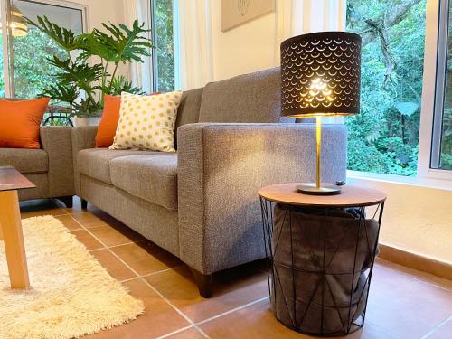 a living room with a couch and a lamp on a table at Casa del Arroyo 2-Bedroom Cottage Fireplace and BBQ in Jarabacoa