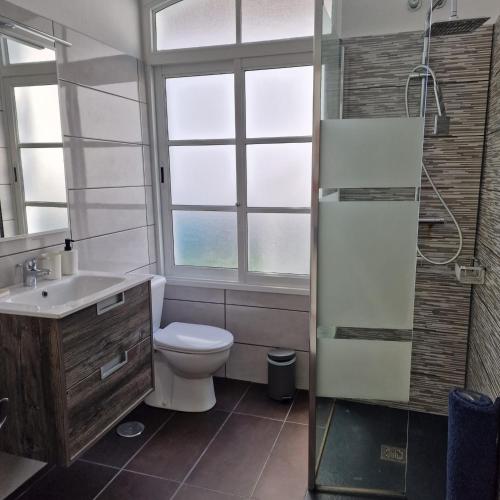 a bathroom with a toilet and a sink and a window at Nora Retreat (Fully Renovated) in Corralejo