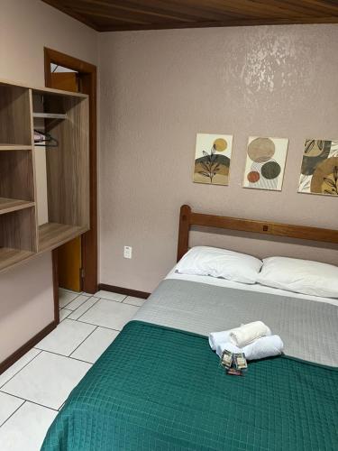 Pousada da Praia Imbé في إمبي: غرفة نوم بسرير وبطانية خضراء ومناشف