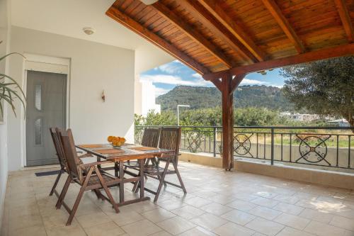 a wooden table and chairs on a patio with a balcony at Propodes Luxury Villa in Pastida