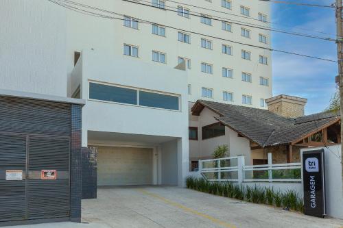 a white building with a garage in front of it at Tri Hotel Executive Osório in Osório