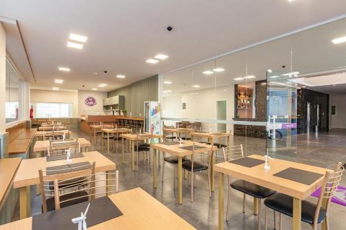 an empty restaurant with wooden tables and chairs at Tri Hotel Executive Osório in Osório