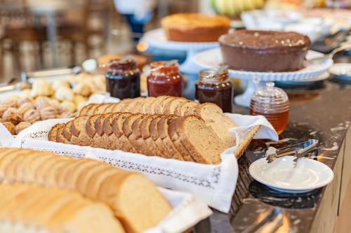 a buffet filled with different types of bread and desserts at Tri Hotel Executive Osório in Osório