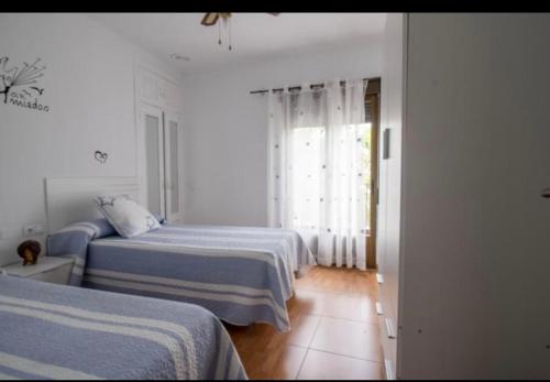 Habitación blanca con 2 camas y ventana en Vivienda con Fines Turísticos Salvador en Úbeda