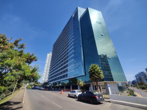 a tall glass building with cars parked in front of it at Vision otima localização vista incrível e muitas comodidades in Brasilia