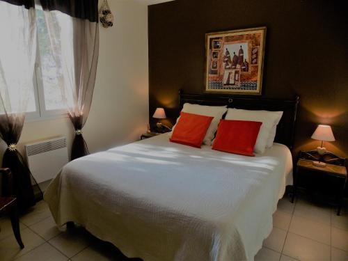 um quarto com uma cama grande e 2 almofadas vermelhas em Les coronilles em Beaucaire
