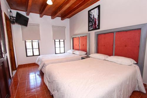 a room with two beds and a television in it at Hotel Casa Autora 40 in Guanajuato