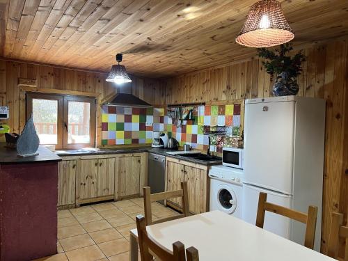 Una cocina con refrigerador y una mesa con sillas. en Las Tejeruelas Casa Rural, en Navacepedilla de Corneja