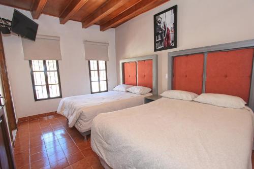 a bedroom with two beds and a tv on the wall at Hotel Casa Autora 40 in Guanajuato