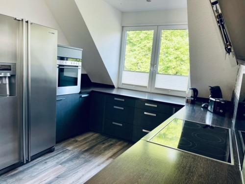 uma cozinha com armários pretos e um frigorífico de aço inoxidável em Apartment 160qm 5 Schlafzimmer 1 Wohnzimmer Terrasse und Balkon em Wilhelmshaven