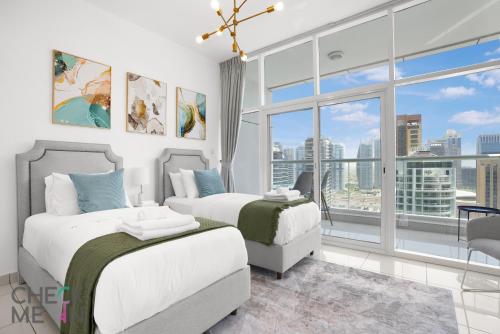 een slaapkamer met twee bedden en een groot raam bij Luxury 2BR with Breath-taking Dubai Marina Views in Dubai