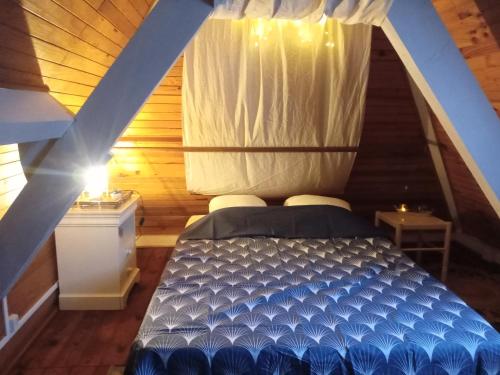 - une chambre mansardée avec un lit bleu dans l'établissement Maison de poupée et son SPA privatif, à Orthez