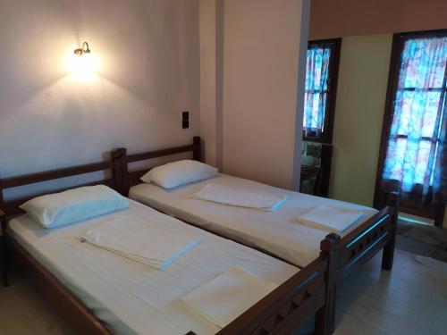 two twin beds in a room with two windows at Double studio room with two single beds in Tsagarada