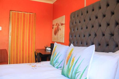 a bedroom with a bed with an orange wall at 7th Dimension Guesthouse in Zeerust