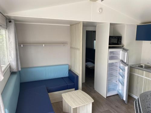 ナルボンヌ・プラージュにあるMobil-home Confort TV CLIM Narbonne-Plageの青いベンチ、オープン冷蔵庫が備わる小さな客室です。