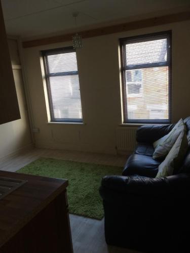 uma sala de estar com um sofá e duas janelas em Hockham em Kings Lynn