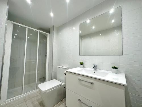 a white bathroom with a toilet and a sink at Domuum Holidays - BARCELONA Family Home in Salou
