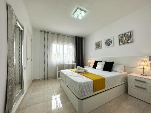 a white bedroom with a bed and a window at Domuum Holidays - BARCELONA Family Home in Salou