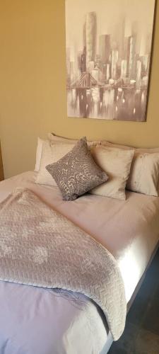 a bed with pillows and a picture on the wall at Doyle's self-catering accommodation in Kimberley
