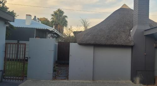 a house with a thatch roof and a white fence at Doyle's self-catering accommodation in Kimberley