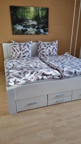 Una cama con cajones blancos y almohadas. en Schöne 2-Zimmer Ferienwohnung en Löffingen