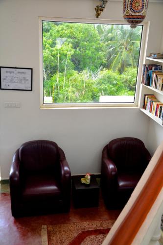two leather chairs in a living room with a window at Holi-Wood Guesthouse in Puducherry