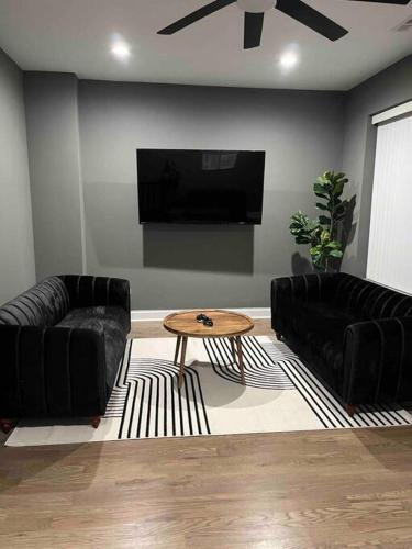 una sala de estar con 2 sofás de cuero negro y una mesa. en Neutral Spiraled Vibes en Chicago