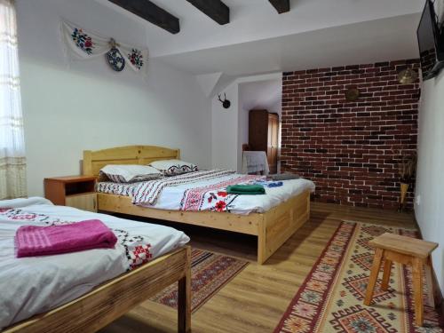 two beds in a room with a brick wall at Casa de Vacanta Neagu in Gura Teghii